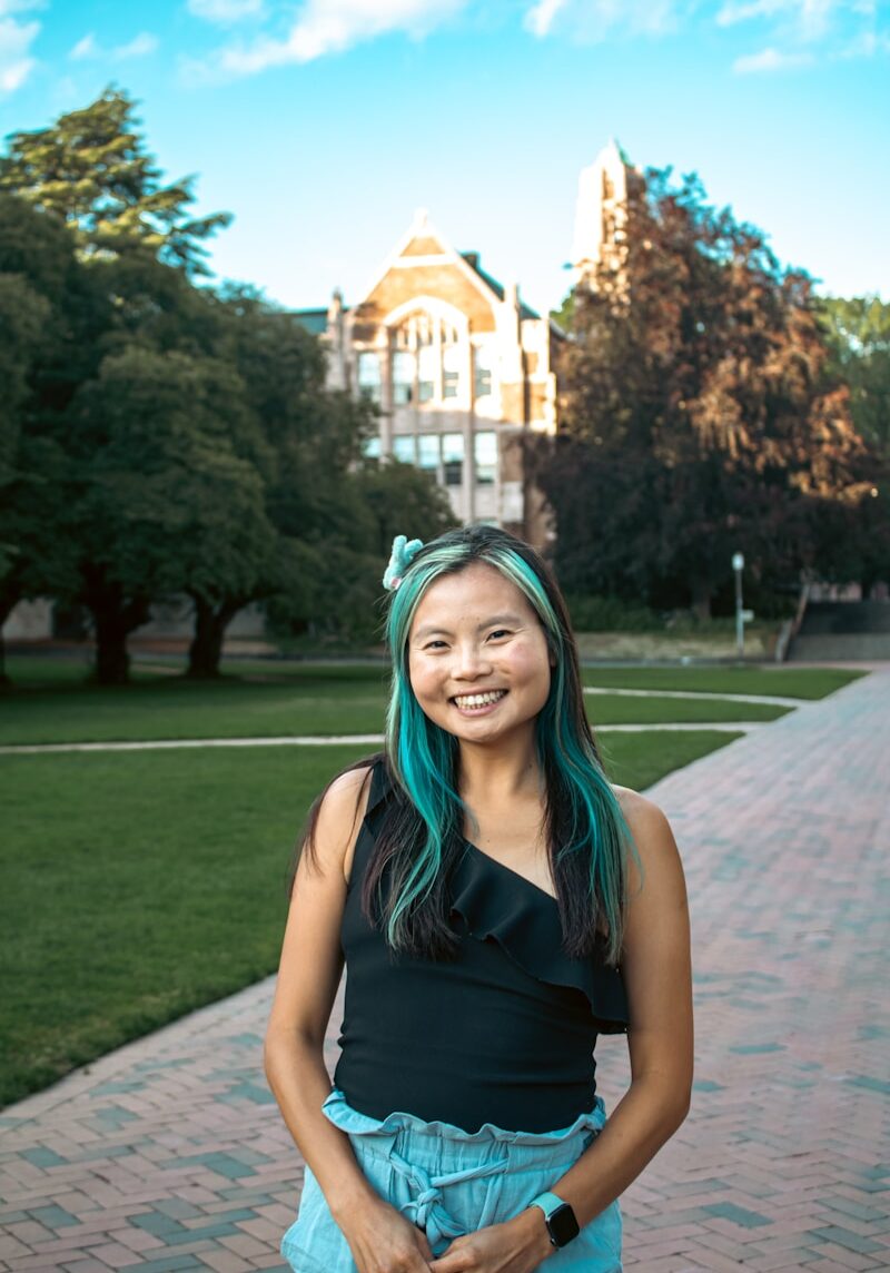 A woman with green hair standing in front of a building